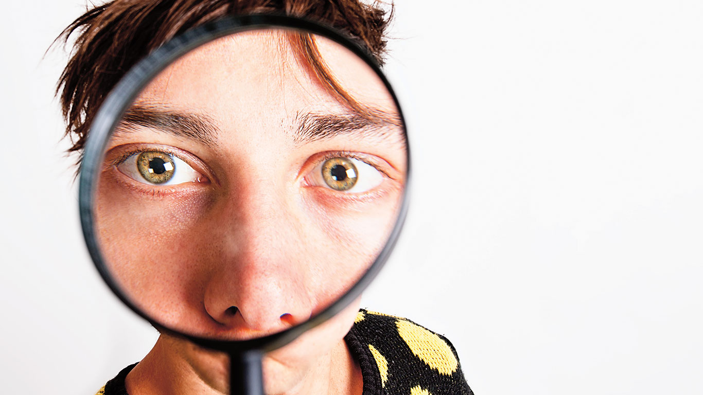 a magnifying glass enlarges a man&apos;s eyes