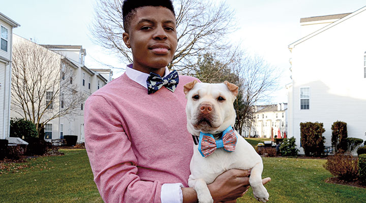 a boy wearing a bowtie holding a dog wearing a bowtie