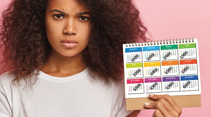 a girl holding up a calendar with "school" written on every month