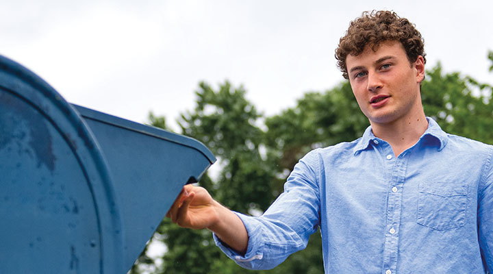 A young man places something into a mail box.