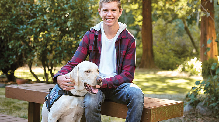A young boy smiles with his dog.