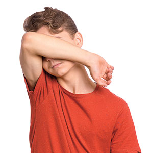 a boy hiding his face behind his elbow