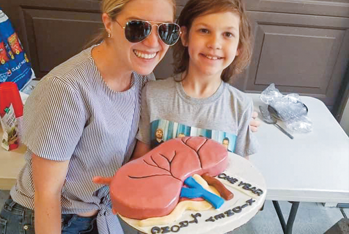 Two people posing with a kidney-shaped cake