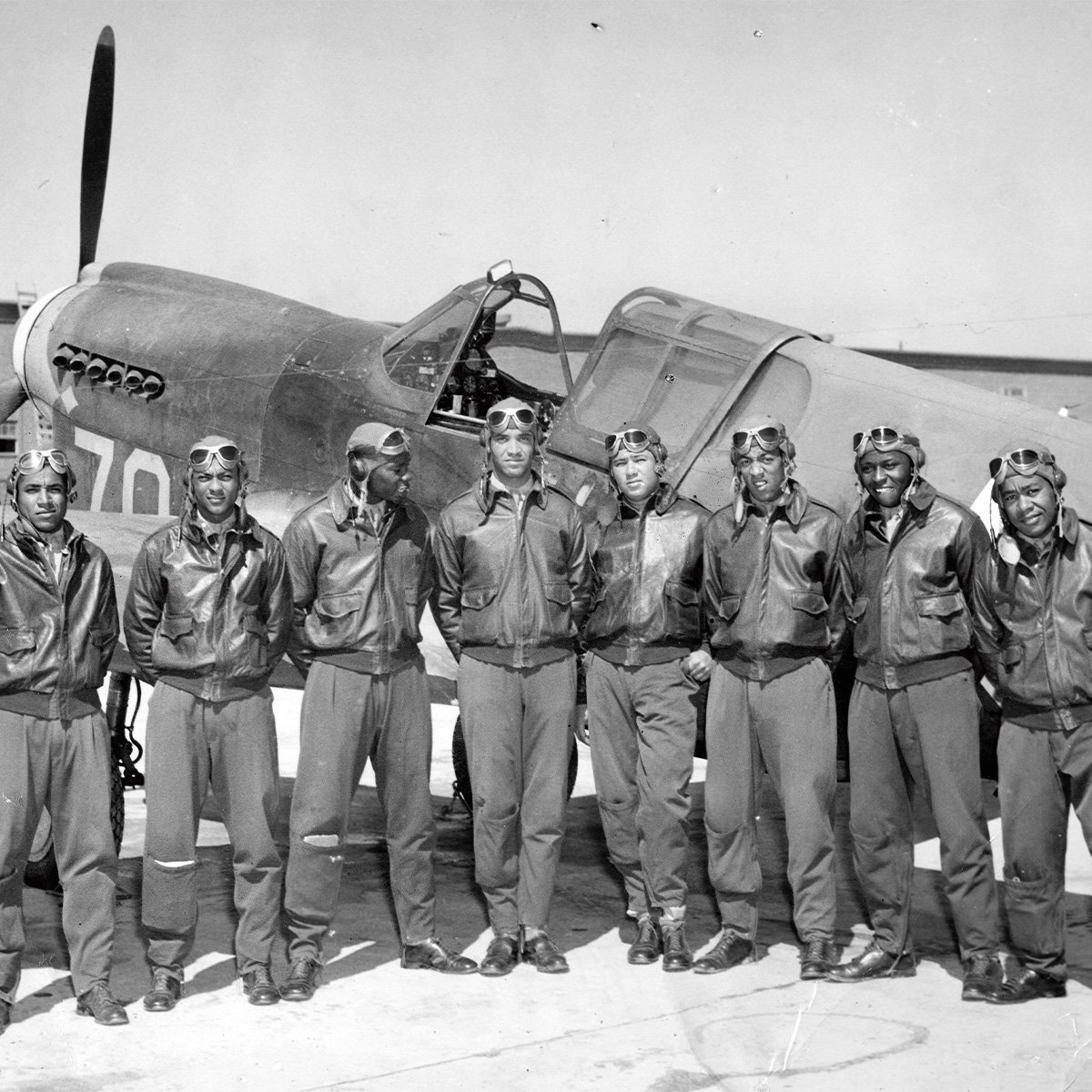 Black & white image of the Tuskegee Airmen posing in front of a fighter plane
