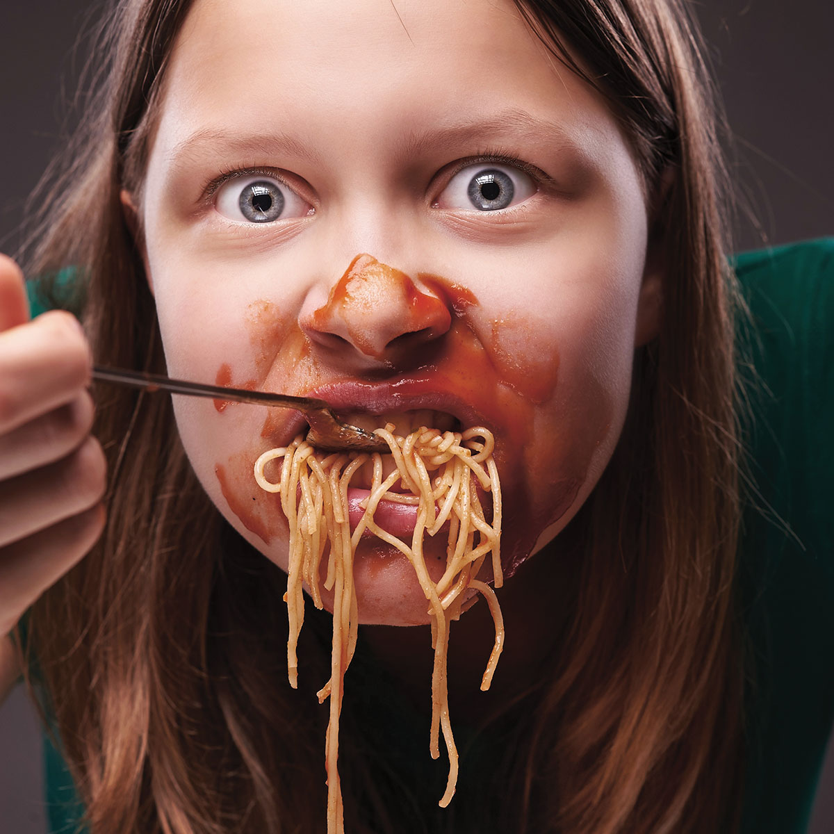 Photo of a teen eating spaghetti with sauce all over face