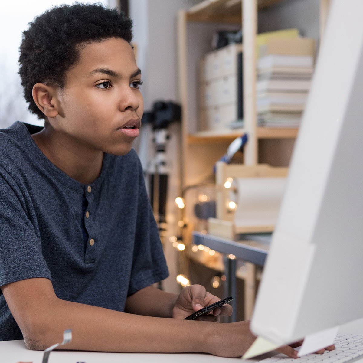 Photo of a teen using phone while on computer