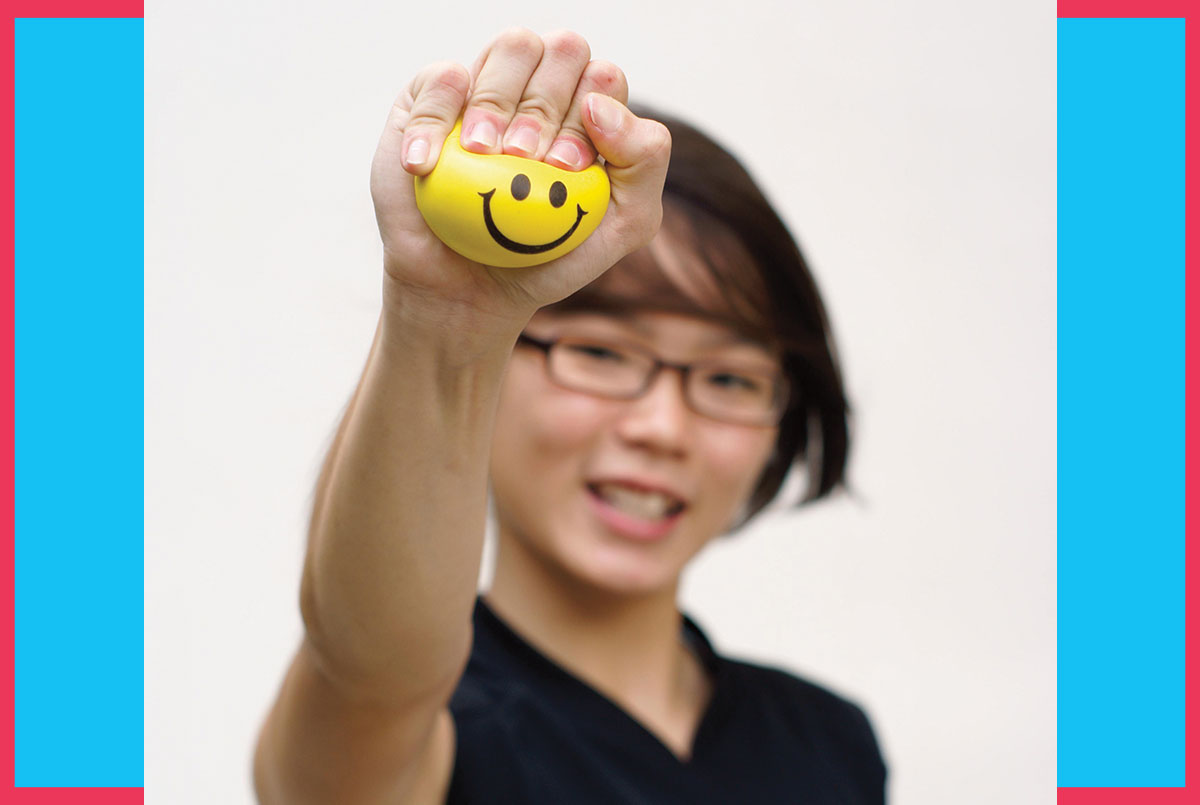 Image of a person holding a smiley face stress ball