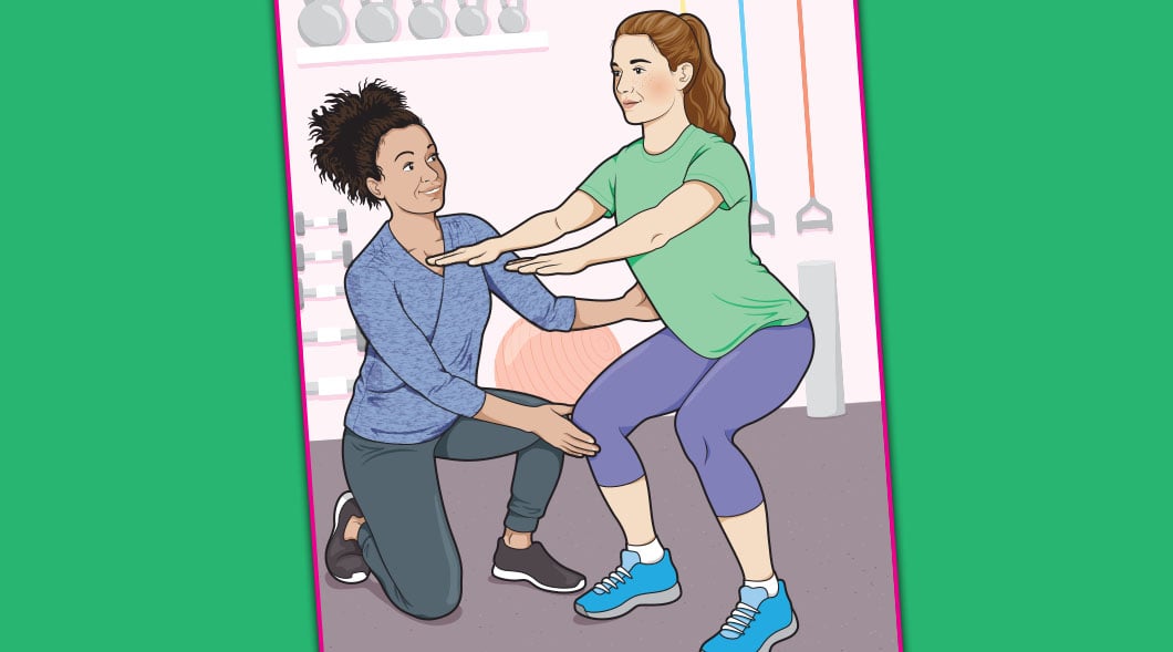 One woman kneels to guide another woman's squat form in a gym