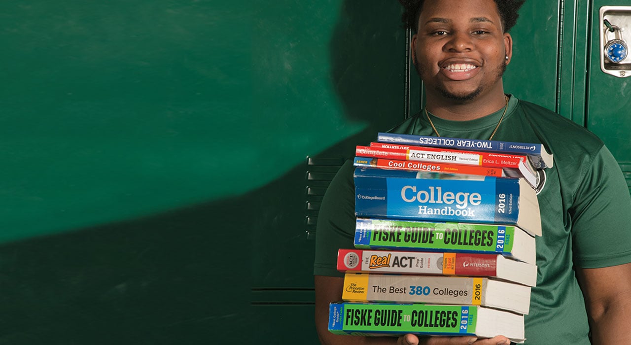 A boy standing with a stack of books