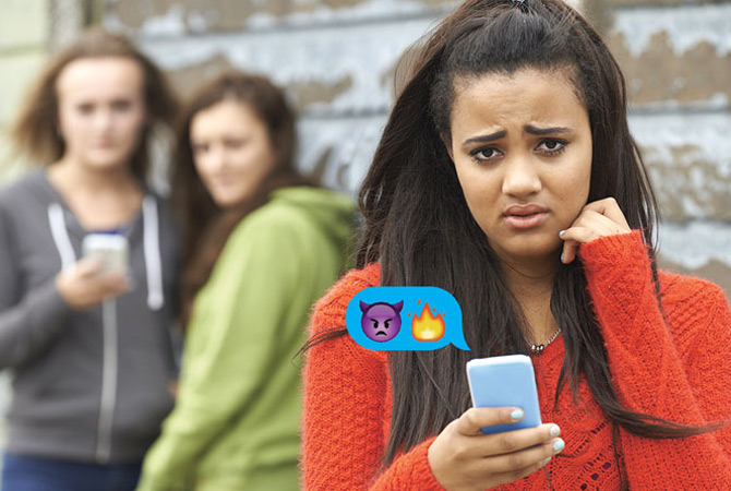 Two girls texting mean emojis to one girl
