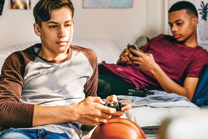 enlargeable photo: two boys playing with their phones and a video game controller