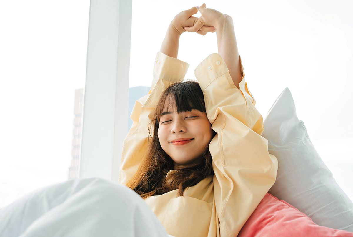 a  girl stretches her arms over her head while in bed