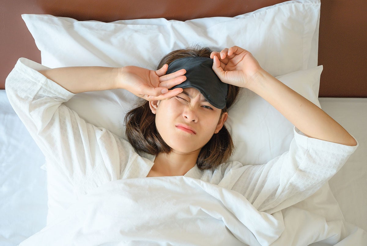 a girl taking off an eye mask with an annoyed expression on her face